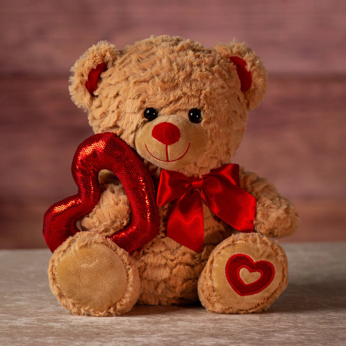 plush bear's embroidered heart on paw and shiny heart decoration
