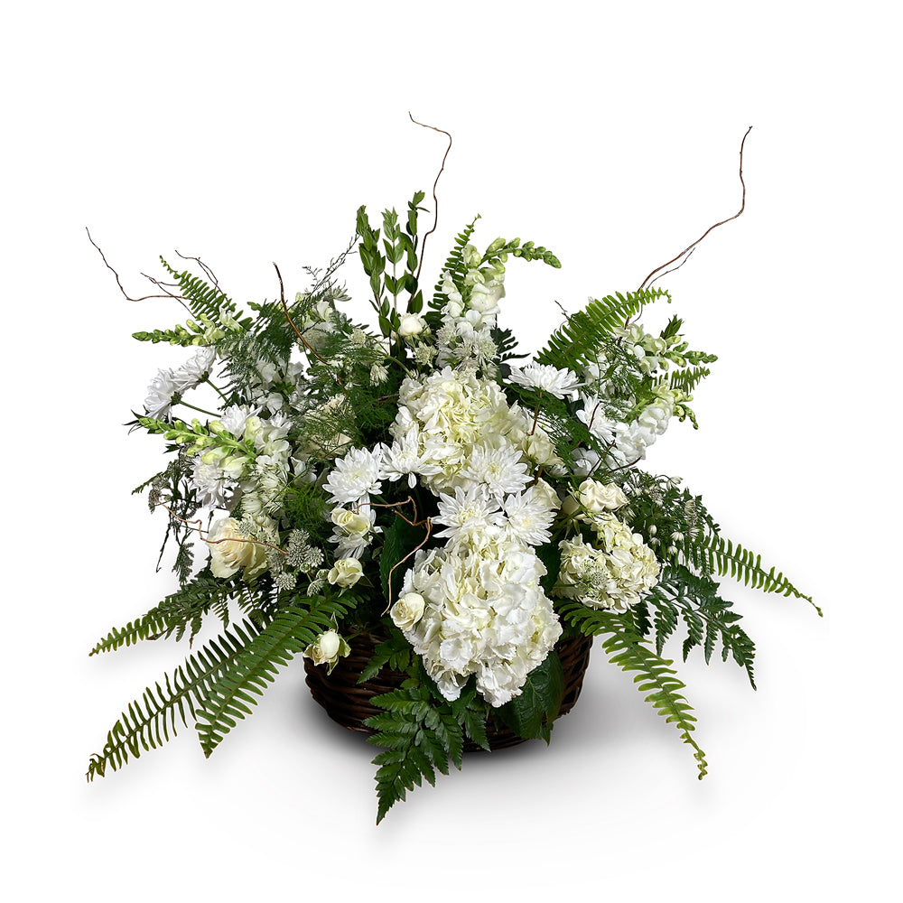 wicker basket with arrangement of white roses hydrangeas and greens